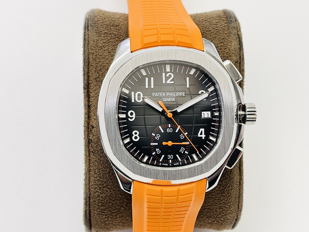 Close-up of a Patek Philippe watch on a display cushion with an orange strap and textured dial.
